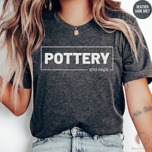 May include: A heather dark grey t-shirt with the text "POTTERY and naps" printed in white.
