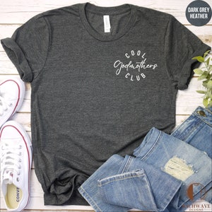 May include: A dark grey heather t-shirt with the text "COOL GODMOTHERS CLUB" in white lettering.