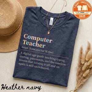 May include: Heather navy t-shirt with the text "Computer Teacher" in colorful letters. The shirt includes a definition and a description of a computer teacher's role. A gold necklace and a straw hat are also visible.
