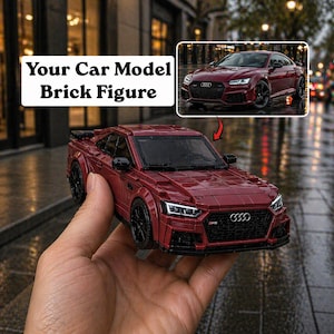 Op de afbeelding: Een bakstenen model van een bordeauxrode sportwagen, met zwarte wielen en afwerking. De modelauto is een replica van een echt voertuig, met de tekst "Your Car Model Brick Figure" in een witte doos op de achtergrond.