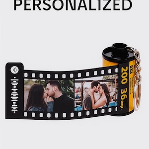 May include: A personalized film roll keychain with two photos of a couple kissing. The film roll is yellow and black, with the text "200 36 exp." printed on it. The word "PERSONALIZED" is at the top.