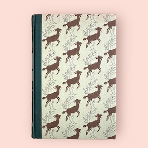 May include: A vintage hardcover book with a green spine and a brown and white pattern of goats on the cover.