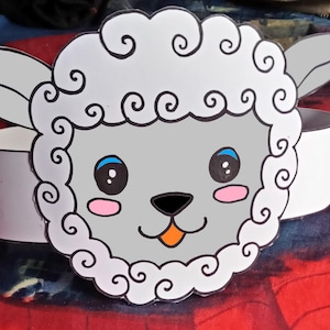 May include: A white paper craft mask of a cartoon sheep with black eyes, a pink nose, and an orange tongue. The sheep has a white headband attached to the back of the mask.
