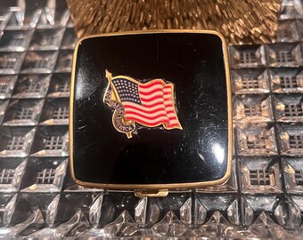 Kompaktowy zestaw do makijażu Vintage Americana z lat 30. Elegancka czarna emalia z motywem flagi amerykańskiej i złotymi zdobieniami. Kompaktowy puder i róż.