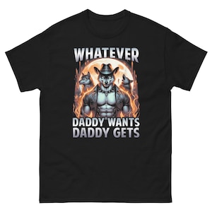 May include: Black t-shirt with a graphic of a wolf-like character wearing a hat and jacket, with the text "WHATEVER DADDY WANTS DADDY GETS". The design features a full moon and flames.