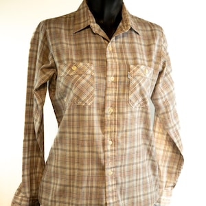 May include: A long-sleeved, button-down shirt in a plaid pattern. The shirt features a beige, brown, and blue color scheme with two chest pockets and a classic collar. The shirt is displayed on a black mannequin.
