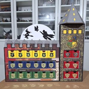 Pode incluir: Um calendário do advento com tema de Hogwarts com 24 portas numeradas. O calendário tem a forma de um castelo com uma torre e uma lua com silhuetas de bruxas e magos voando em vassouras. As portas são decoradas com glitter e têm cores e designs diferentes.