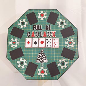 Peut inclure: Un plateau de jeu octogonal avec un motif de grille verte, comprenant des cartes à jouer, des jetons de poker et le texte "FULL DE CADEAUX". Le plateau comprend un motif de sapin de Noël et des emplacements pour les cartes.
