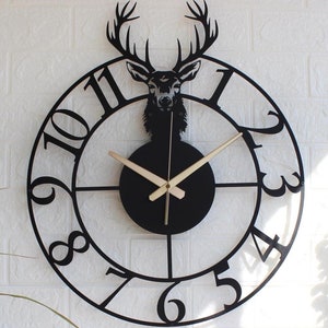 May include: Black metal wall clock with a deer silhouette and Roman numeral hour markers. The clock has gold-colored hands.