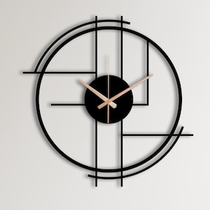 May include: A black and white geometric wall clock with gold hands hanging on a white wall above a light blue and white cabinet. The cabinet is decorated with stuffed toys and a yellow cat pillow.