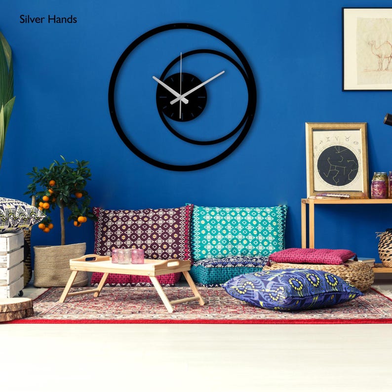 Pu&ograve; includere: Un orologio da parete nero e moderno con un design a spirale unico. L'orologio presenta lancette argentate e un quadrante nero, su una parete blu brillante. Il testo "Silver Hands" &egrave; visibile nell'angolo in alto a sinistra.