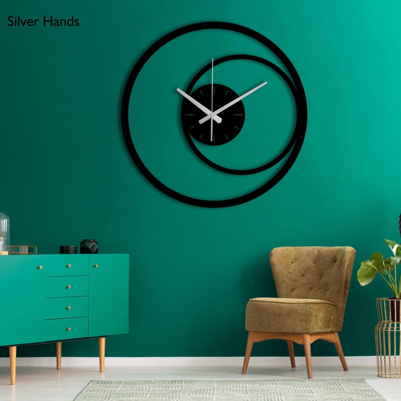 Pu&ograve; includere: Un moderno orologio da parete nero con lancette argentate e un design a spirale unico. Il quadrante dell'orologio &egrave; nero e le lancette sono argentate. L'orologio &egrave; montato su una parete verde acqua. Il testo "Silver Hands" &egrave; nell'angolo in alto a sinistra.