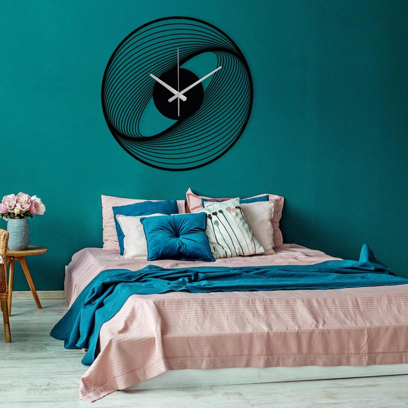 Silent, modern, spiral metal wall clock with silver hands, hanging on the blue wall, in the bedroom.