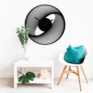 May include: A modern black and white wall clock with a unique, swirling design. The clock face is black, and the hands are black. The clock is mounted on a white wall. The clock's diameter is approximately 20 inches.
