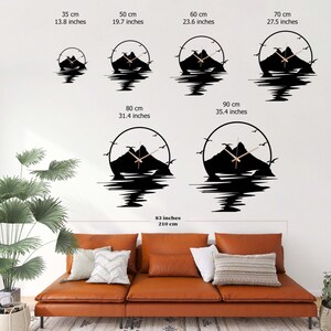 May include: Six circular wall clocks featuring a black mountain silhouette with birds and water reflection. Sizes range from 13.8 inches to 35.4 inches in diameter, displayed above a brown leather sofa measuring 83 inches in total width.