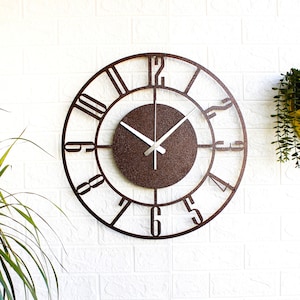 K&ouml;nnte beinhalten: Eine gro&szlig;e, runde, braune Wanduhr aus Metall mit r&ouml;mischen Ziffern und einem kleineren, runden, braunen Zifferblatt. Die Zeiger der Uhr sind silberfarben.