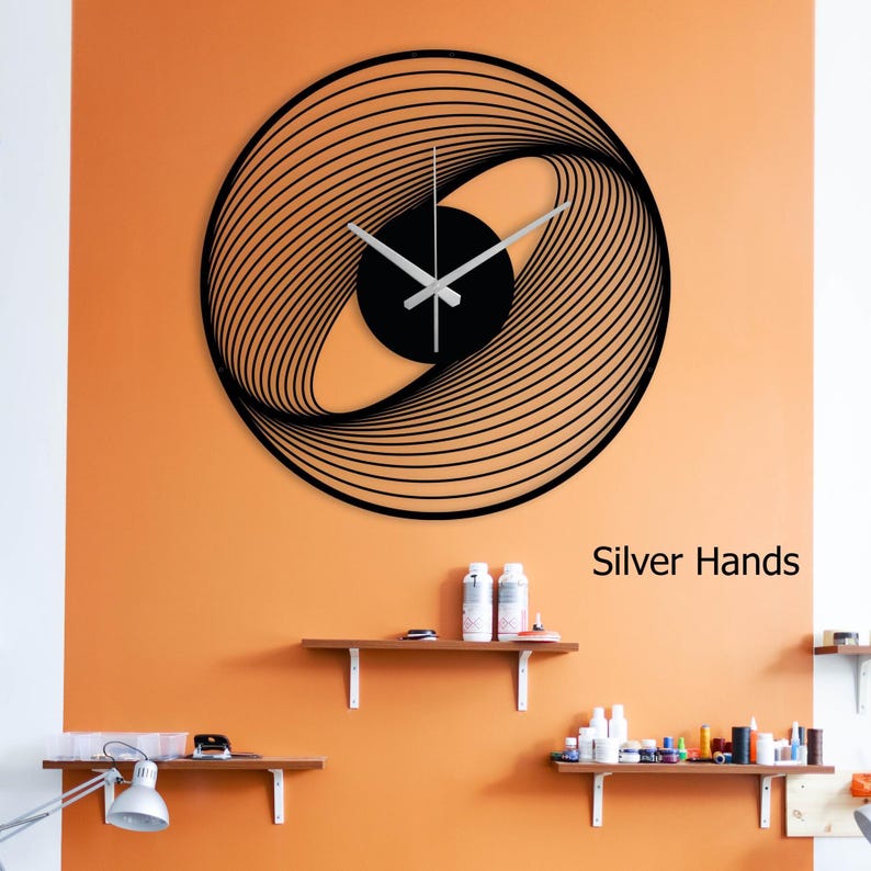 May include: A black, modern wall clock with a unique, swirling design. The clock features silver hands and a black center. The text "Silver Hands" is visible on the wall. The clock is mounted on an orange wall.