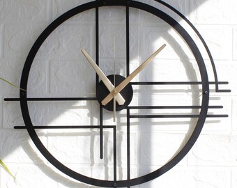 Könnte beinhalten: Eine schwarze Wanduhr aus Metall mit goldfarbenen Zeigern und geometrischem Design. Die Uhr hat einen runden Rahmen mit einer Reihe von sich kreuzenden Linien.