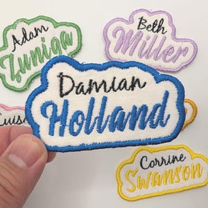 May include: Five embroidered patches with names in a cloud shape. The patches are in different colors: green, purple, blue, pink, and yellow. The names on the patches are Adam Zumiga, Beth Miller, Damian Holland, Luisa, and Corrine Swanson.