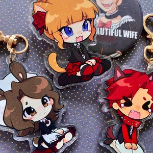 May include: A collection of anime-style character keychains and a button. The keychains feature various characters with animal ears, dressed in black and red outfits. The button reads "I LOVE BEAUTIFUL WIFE".
