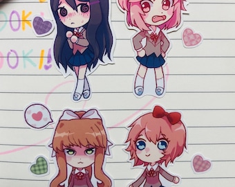 May include: Four colorful anime character stickers with different expressions. The stickers are on a lined notebook page with pink and green hearts.