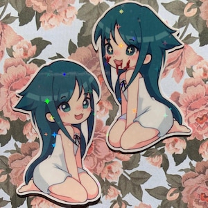 Puede incluir: Dos pegatinas de dibujos animados de chicas de anime con cabello largo azul que llevan vestidos blancos. Las chicas tienen ojos rojos y sonríen con sangre en la boca.