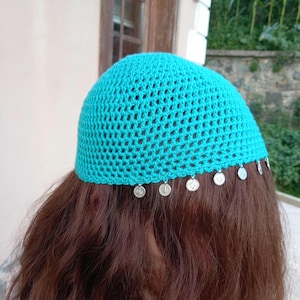 May include: A bright turquoise crochet skull cap featuring a delicate open-stitch pattern. The lower edge of the cap is adorned with a series of small, round, silver-toned metal charms that hang evenly spaced around the entire circumference.