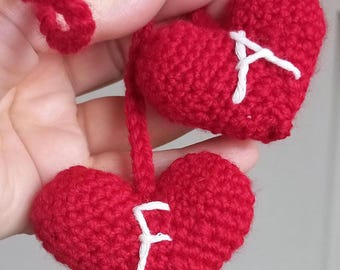 May include: Two red crocheted hearts with white letters, one heart says "A" and the other says "F".