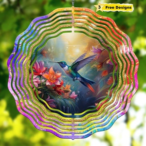 May include: A colorful metal wind spinner with a hummingbird and flowers design. The spinner has multiple layers of swirling colors, including pink, purple, blue, and green. The hummingbird is flying through a field of flowers, and the background is a soft, blurred image of a forest.