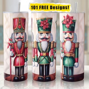 Op de afbeelding: Drie roestvrijstalen bekers met een witte achtergrond en een kerstnootkrakerontwerp. Elke beker heeft een andere nootkraker in rode, groene en blauwe uniformen. De tekst "101 FREE Designs!" staat bovenaan de afbeelding.