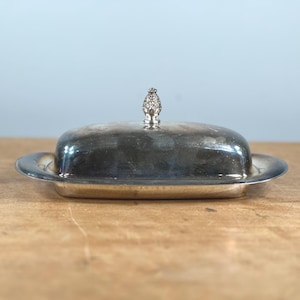 May include: Silver butter dish with a decorative knob on the lid.