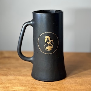 May include: Black ceramic beer stein with a gold Playboy bunny logo and the text "The Playboy Club" repeated around the logo.
