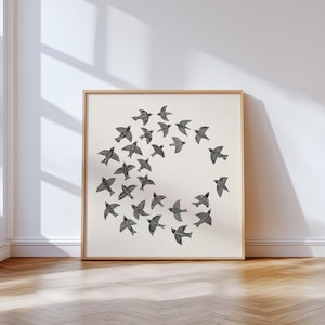 May include: A framed print showing a flock of black birds arranged in a circle on a cream background. The birds have detailed wing patterns. The frame is light wood, and the artwork is displayed on a wall, creating a minimalist aesthetic.