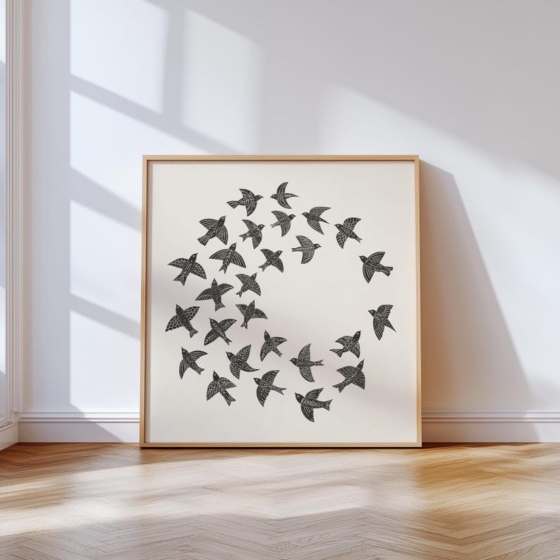 May include: A framed print showing a flock of black birds arranged in a circle on a cream background. The birds have detailed wing patterns. The frame is light wood, and the artwork is displayed on a wall, creating a minimalist aesthetic.
