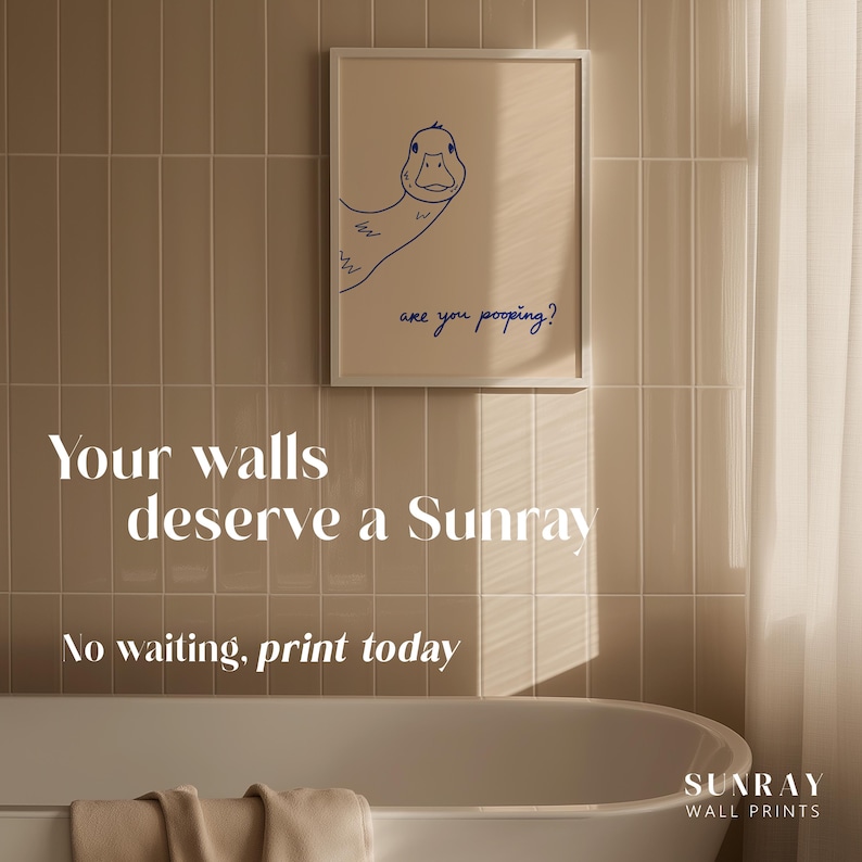 May include: A framed print featuring a blue line drawing of a duck with the text "are you pooping?" on a beige background. The image is displayed on a tiled wall above a bathtub. The text "Your walls deserve a Sunray" and "No waiting, print today" are also visible.