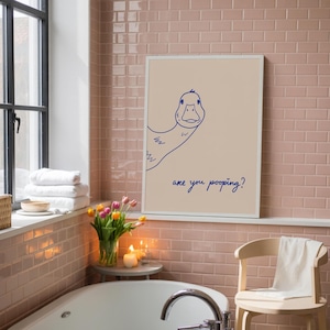 May include: A framed print featuring a whimsical blue line drawing of a duck peeking from the side, with the text "are you pooping?" in a playful font. The artwork is set against a neutral background, adding a touch of humor to any bathroom decor.