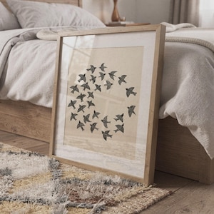 May include: A framed print showing a flock of black birds in a circular formation. The birds have detailed wing patterns and are set against a beige backdrop. The frame is made of light wood, complementing the artwork's natural theme.