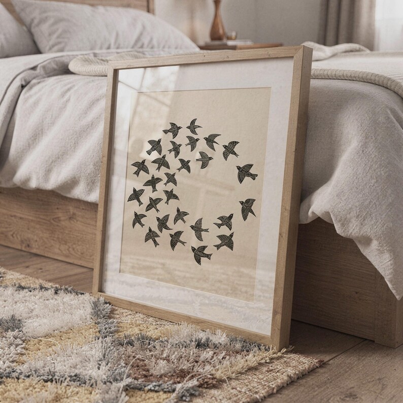 May include: A framed print showing a flock of black birds in a circular formation. The birds have detailed wing patterns and are set against a beige backdrop. The frame is made of light wood, complementing the artwork's natural theme.