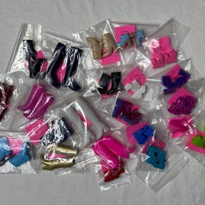 May include: Assortment of colourful plastic doll shoes and boots in various styles and sizes, packaged in clear plastic bags.