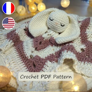 Peut inclure: Une couverture bébé en crochet avec un lapin blanc attaché. La couverture est rose et blanche avec un motif en chevron. Le texte "Crochet PDF Pattern" est visible en bas de l'image.