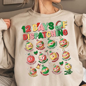 Könnte beinhalten: Ein beiger Pullover mit einem weihnachtlichen Design, das den Text "12 Days of Dispatching" und eine Reihe von Ornamenten mit verschiedenen Sätzen zum Thema Dispatching zeigt, wie z. B. "Traffic Stops", "Spouse Yelling" und "Cars a Blazing".