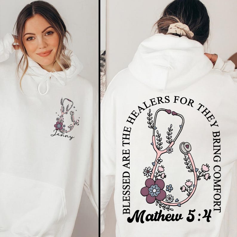 May include: White hoodie with a floral stethoscope design. The front features a stethoscope with flowers and the name "Jenny". The back displays a stethoscope design with the text "Blessed are the healers for they bring comfort" and "Mathew 5:4".