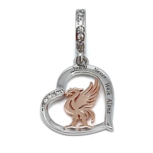 May include: A silver heart-shaped charm with a rose gold bird emblem. The charm features a loop set with small clear stones. The words "You'll Never Walk Alone" are engraved on the heart.