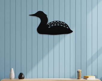 May include: Black metal silhouette of a loon bird mounted on a light blue wall above a wooden shelf with a vase and other decorative items.