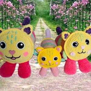Peut inclure: Trois jouets pour chats faits &agrave; la main au crochet. Les chats ont des corps jaunes, des joues roses et des pieds rouges. Les oreilles sont violettes et les yeux sont noirs. Le fond est un chemin avec des fleurs roses.