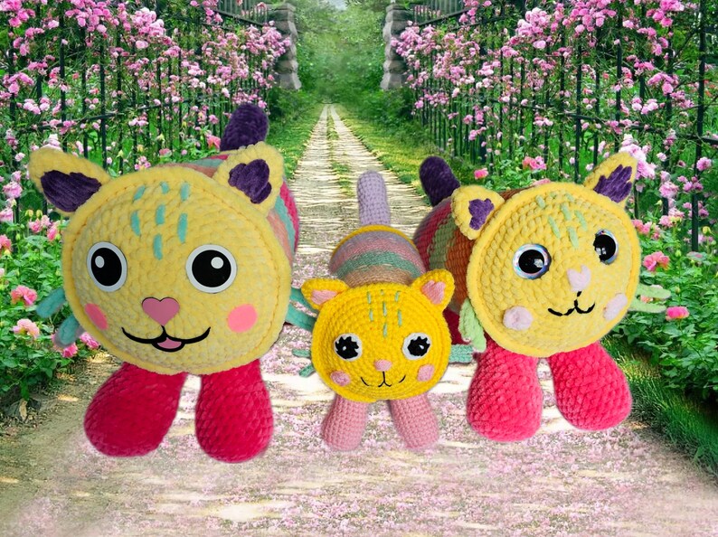 Peut inclure: Trois jouets pour chats faits &agrave; la main au crochet. Les chats ont des corps jaunes, des joues roses et des pieds rouges. Les oreilles sont violettes et les yeux sont noirs. Le fond est un chemin avec des fleurs roses.