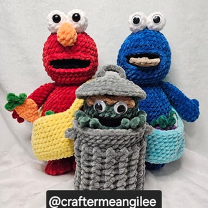 May include: Three crocheted plush toys: a red Elmo, a blue Cookie Monster, and a green character in a gray crocheted trash can. The toys are holding crocheted baskets.