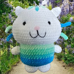 Peut inclure: Un chat en peluche fait &agrave; la main, avec une t&ecirc;te et un corps blancs, des yeux noirs, un nez rose et une bouche souriante. Le bas du corps passe du vert d'eau au bleu. Le chat a de petites oreilles et des accents bleus et verts. Le jouet est fait de fil doux et textur&eacute;.