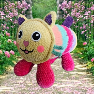 Peut inclure: Un jouet en peluche fait &agrave; la main en forme de chat. La t&ecirc;te est jaune, avec des joues roses et de grands yeux noirs. Le corps pr&eacute;sente des rayures color&eacute;es de turquoise, de rose et de violet. Le chat a des pattes roses et une queue violette. Le jouet est doux et c&acirc;lin.