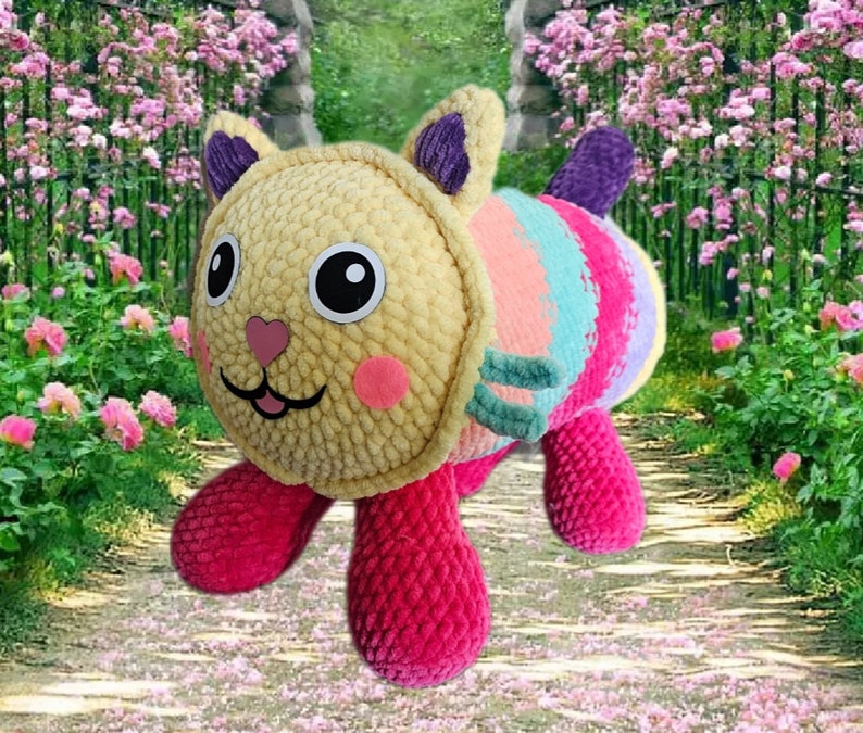 Peut inclure: Un jouet en peluche fait &agrave; la main en forme de chat. La t&ecirc;te est jaune, avec des joues roses et de grands yeux noirs. Le corps pr&eacute;sente des rayures color&eacute;es de turquoise, de rose et de violet. Le chat a des pattes roses et une queue violette. Le jouet est doux et c&acirc;lin.